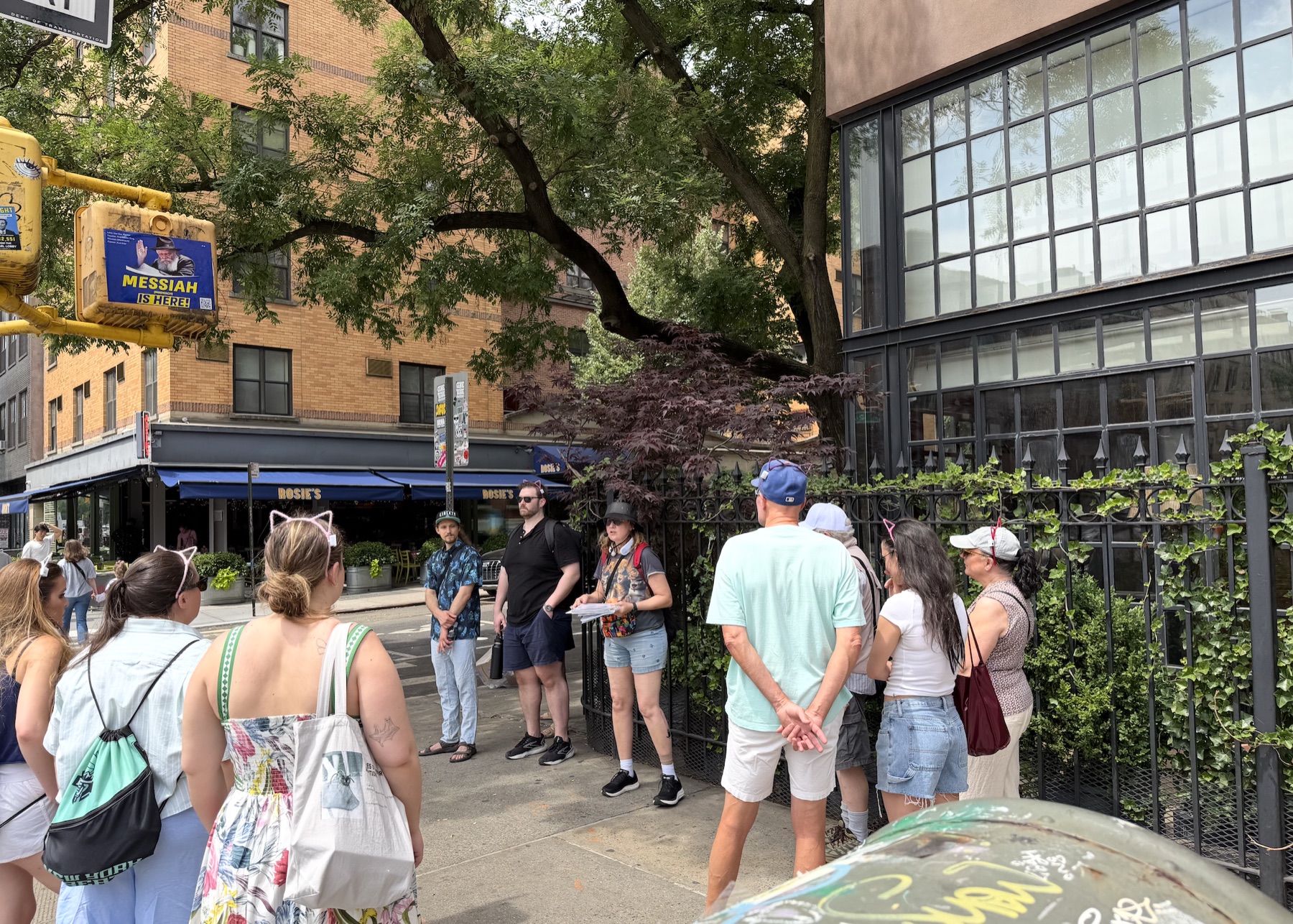 Lower East Side cat history tour guide sharing archival photos with guests on a sunny sidewalk